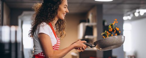 Woman chef cooking vegetables in pan