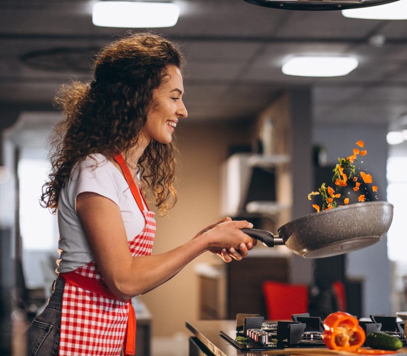 Woman chef cooking vegetables in pan