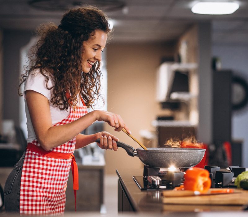 Woman chef cooking vegetables in pan